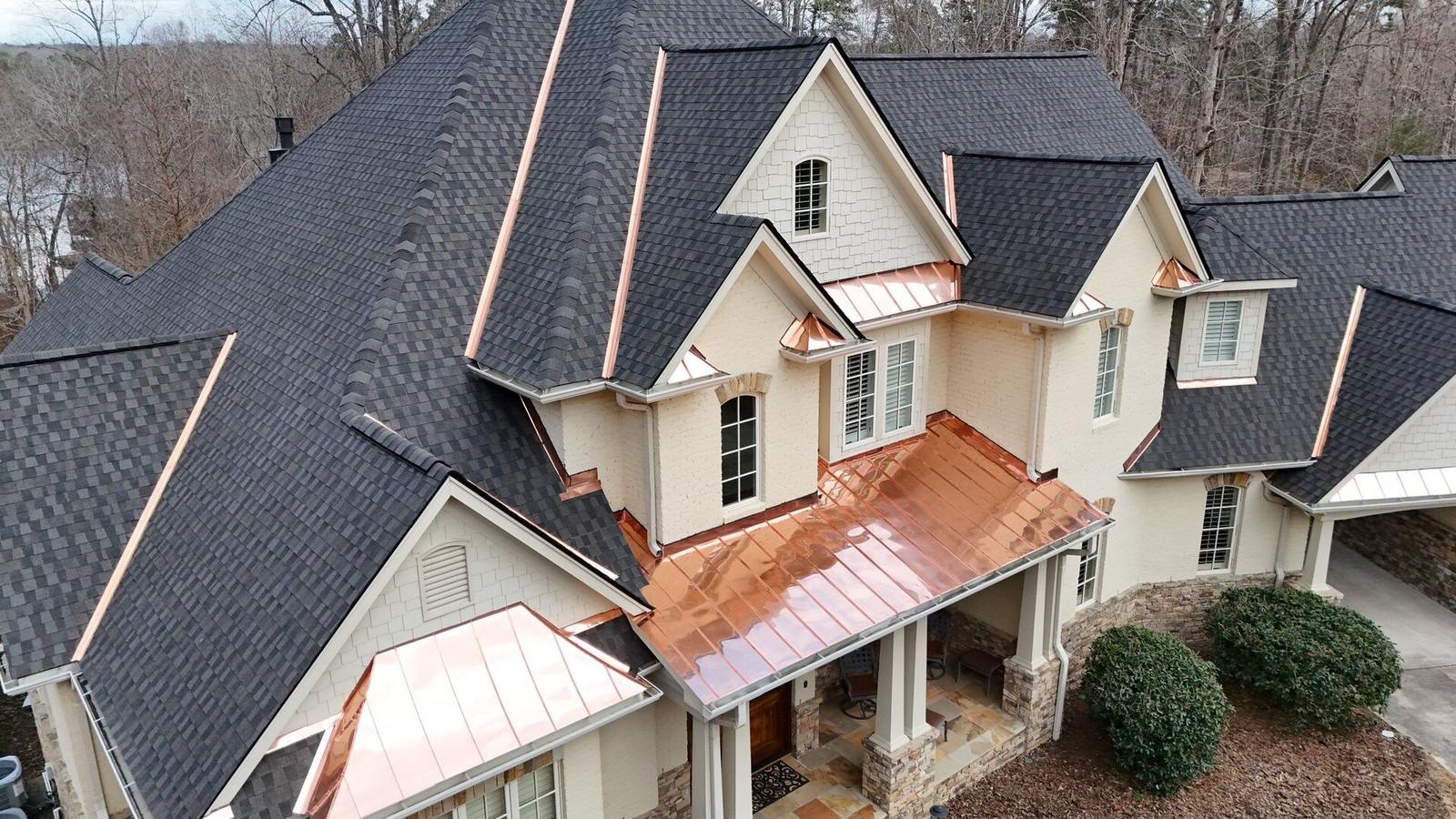 Aerial view of a home with dark architectural shingles and copper metal roof accents