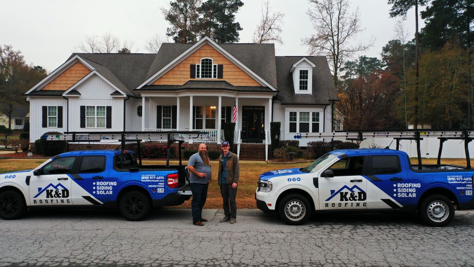 K&D Roofing team and branded trucks in front of a home