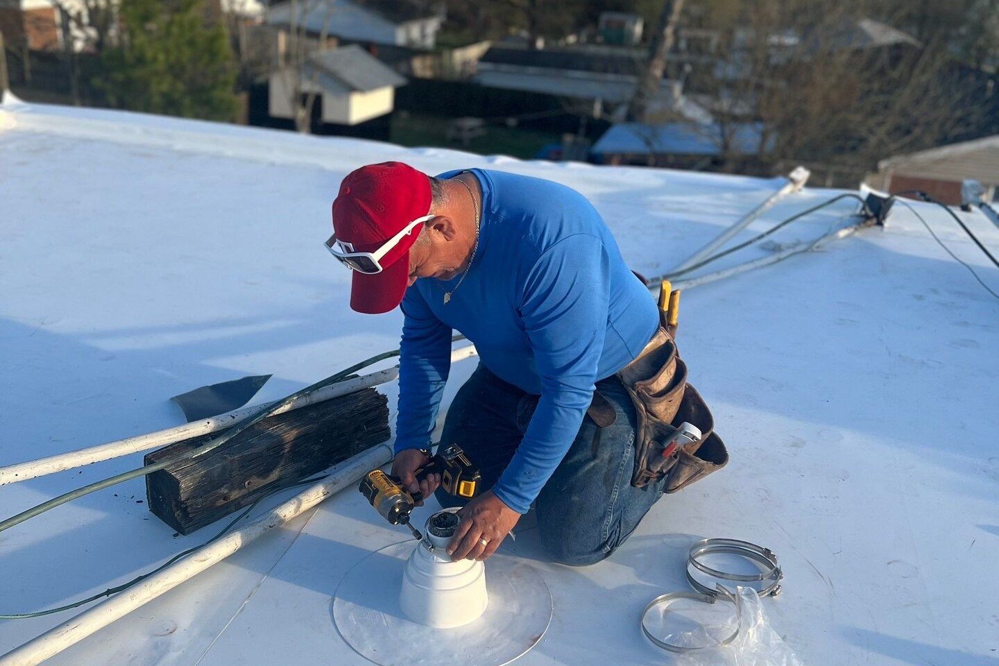 Roofer rolling a TPO membrane seam on a flat roof