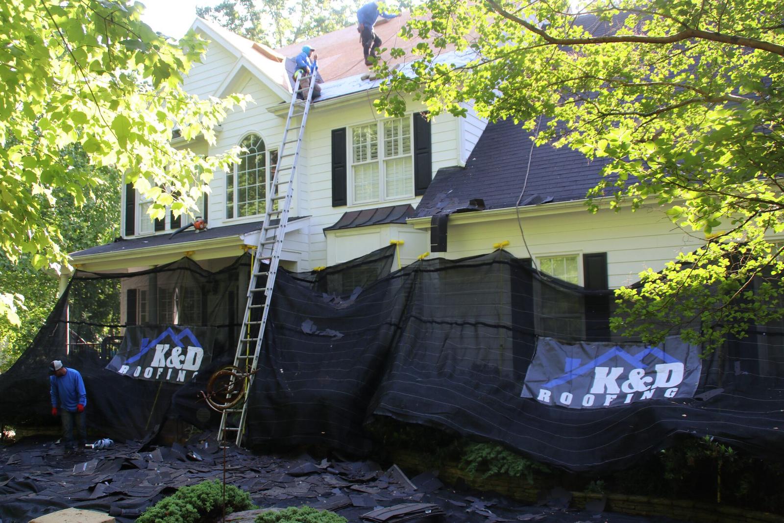 Roof replacement in progress with K&D Roofing tarps protecting the house