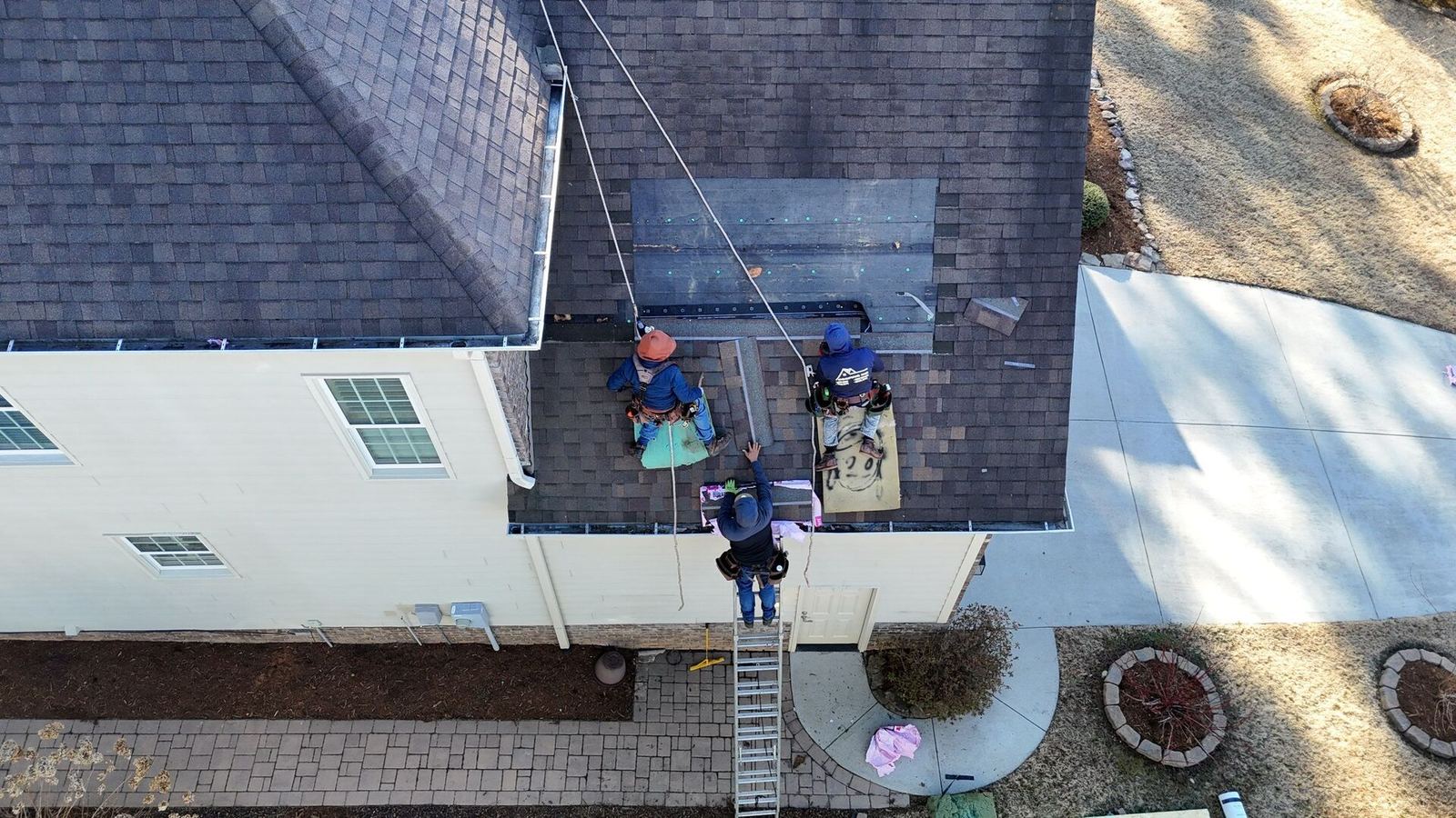 Aerial view of roofers repairing a section of a shingle roof
