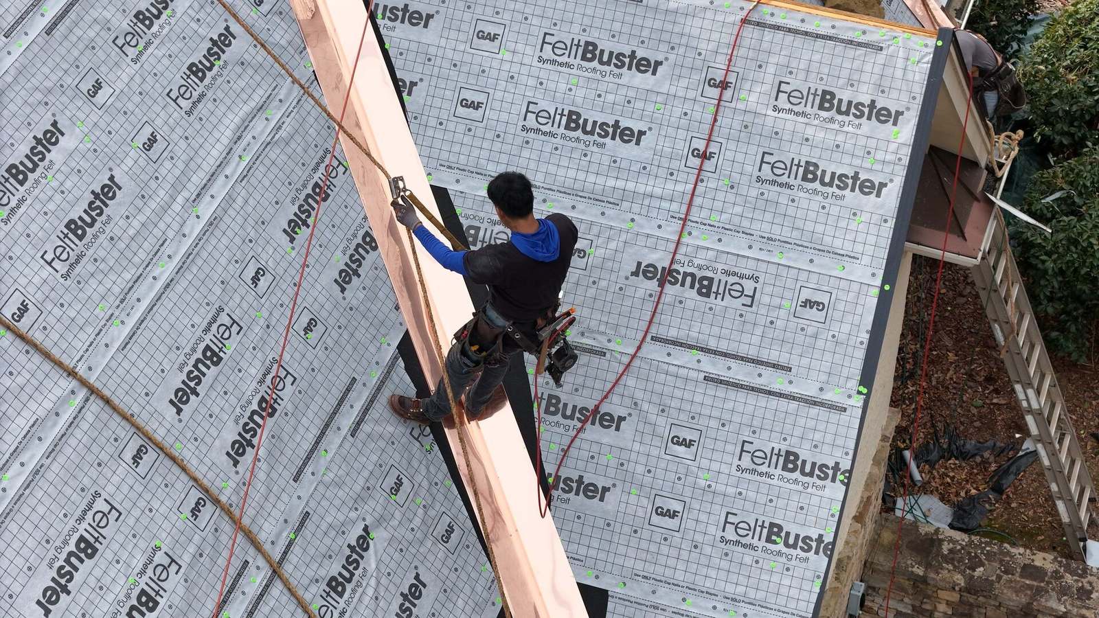 Installer laying a copper metal valley over synthetic underlayment