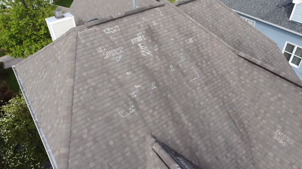 Drone view of a shingle roof with chalk marks from a hail damage inspection