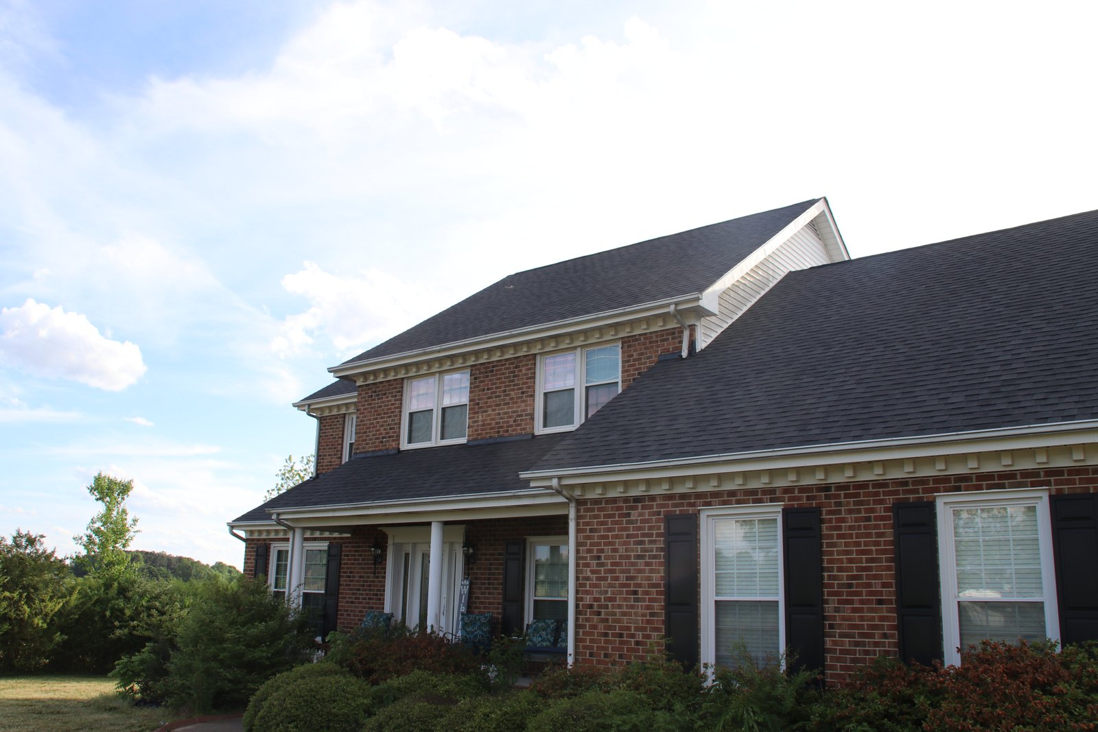 Brick two-story home with a dark gray asphalt shingle roof