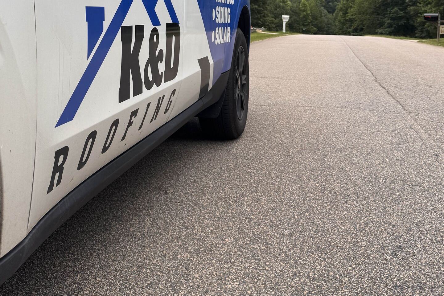 K&D Roofing truck under dark storm clouds