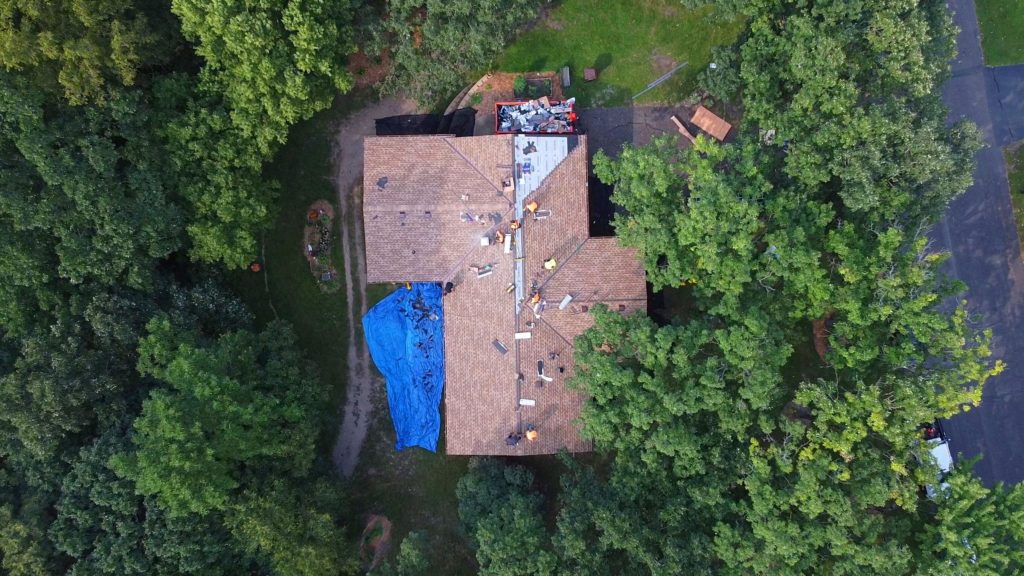 aerial view of home with tarp on roof; how to tarp a roof