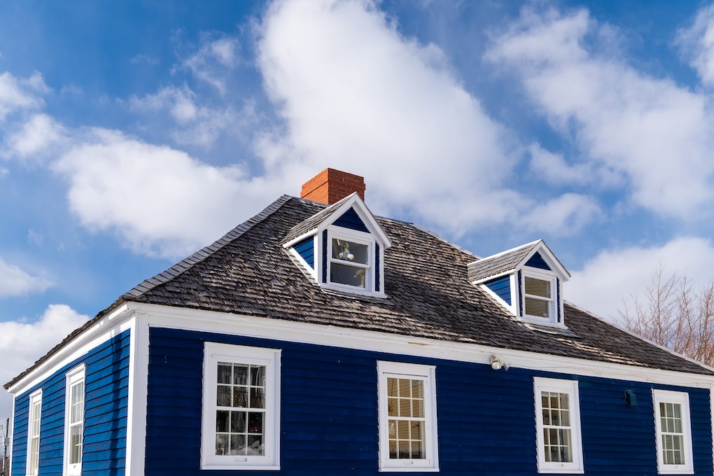 how to clean roof shingles on Navy blue vintage building with white trim and dark roof shingles