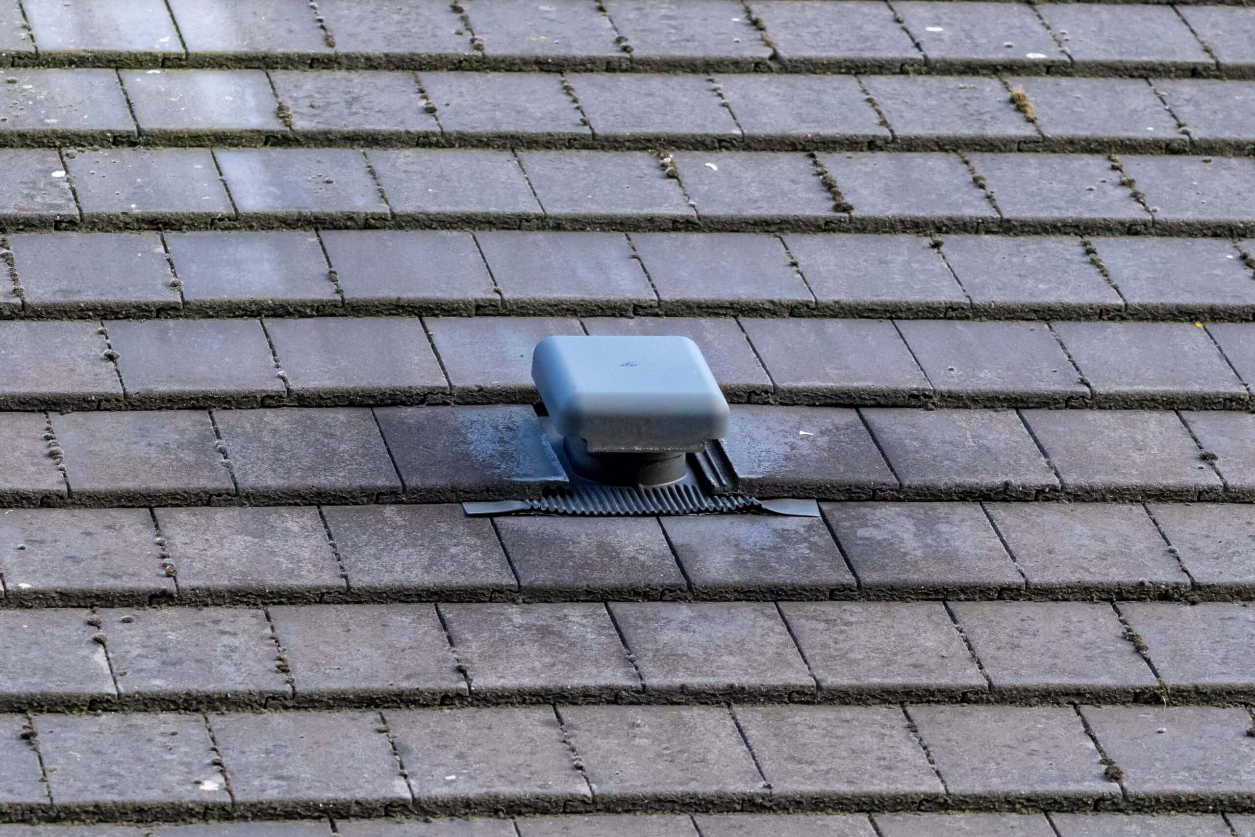 A portrait of a roof vent on a slate roof on a house. This small chimney like object is used as a ventilation, to ventilate a house and regulate the air flow or air supply of a building. slate roof