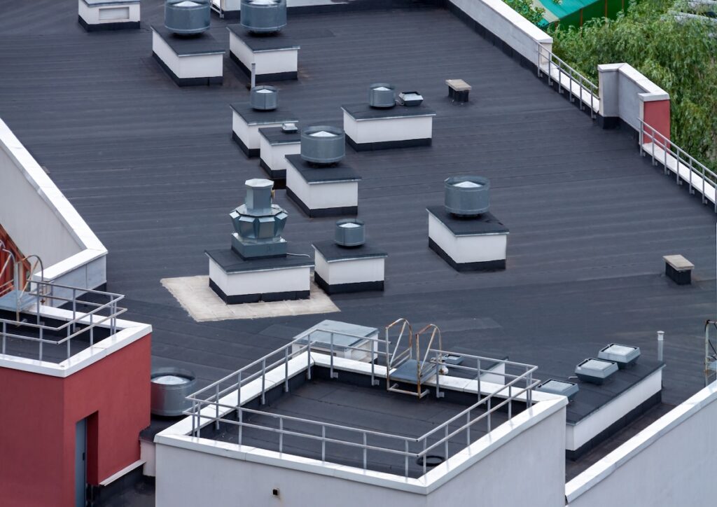 Top view dark flat roof with air conditioners and hydro insulation membranes modern apartment building residential area.