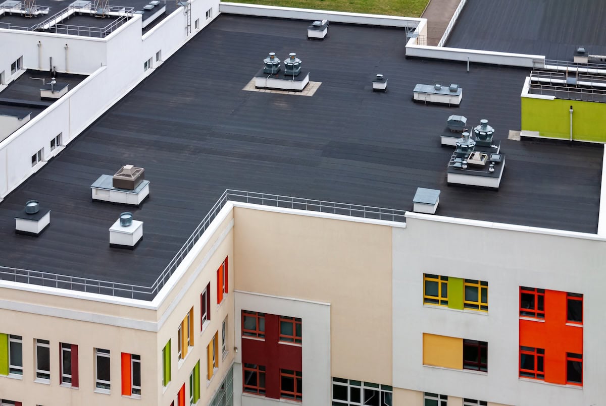 membrane roof Top view flat roof with air conditioners and hydro insulation membranes on top of a modern apartment yellow green red building.